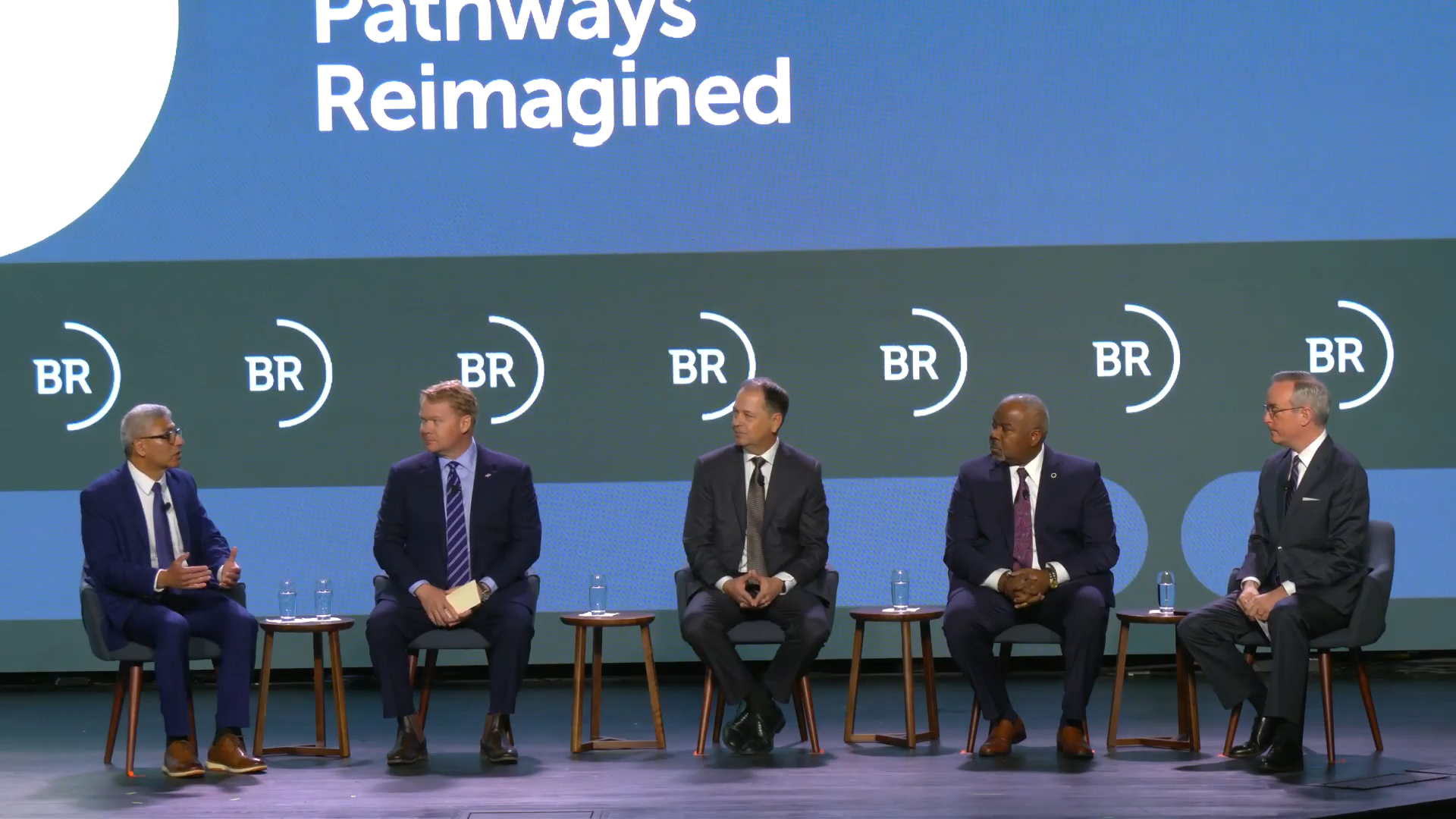 Group of five individuals sits on stage for a panel discussion